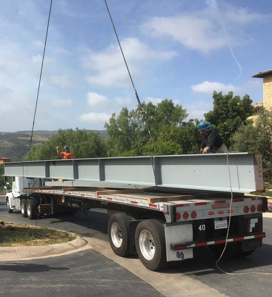 Large wide-flange beam being lifted off a Tobin flatbed